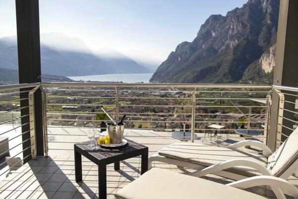 Eine Terrasse mit atemberaubendem Blick auf einen See und Berge. Ein Tischchen mit Wein und Zitronen schafft eine entspannende Atmosphäre.