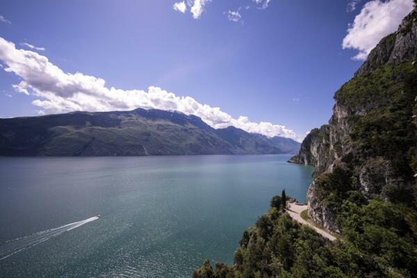 A beautiful lake surrounded by green mountains and cliffs. The sky is clear with white clouds.
