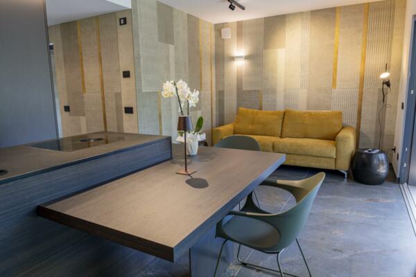 Ein modernes Wohnzimmer mit einem gelben Sofa und einer dekorativen Designwand. Der Tisch und die Stühle vervollständigen die elegante und minimalistische Einrichtung.