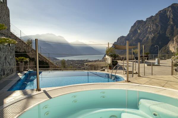 Ein Pool mit Blick auf die Berge und den See. Der Bereich ist modern und sonnendurchflutet.