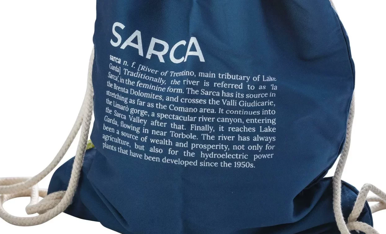 Eine blaue Tasche mit der Aufschrift "Sarca" und Informationen zum Fluss Sarca, einem Nebenfluss des Gardasees. Die Tasche hat auch Schnüre zum Verschließen.