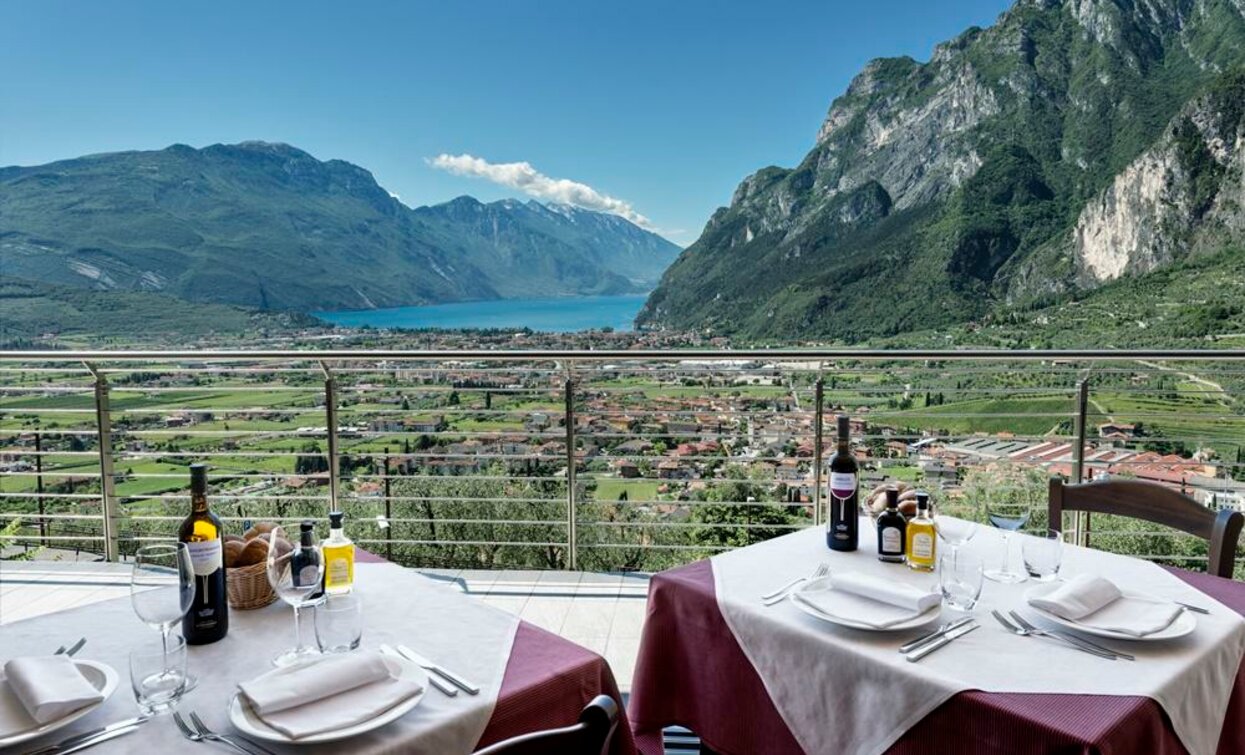 Eine spektakuläre Aussicht auf einen See, der von grünen Bergen umgeben ist. Im Vordergrund stehen elegant gedeckte Tische mit Wein und Dekorationen.