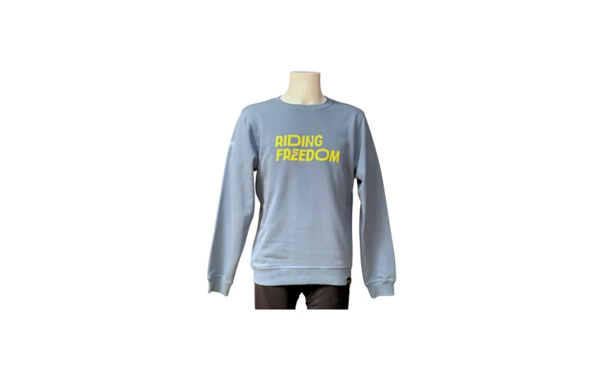 Un maglione azzurro con la scritta "Riding Freedom" in giallo. Perfetto per un look casual e rilassato.